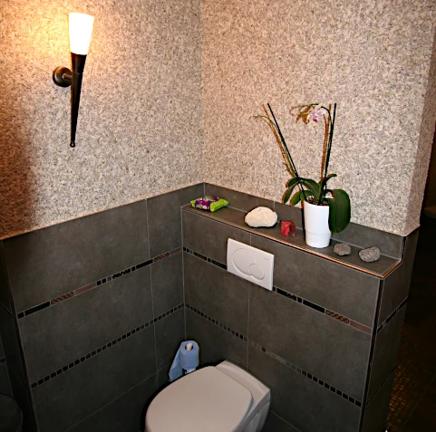 Bad mit WC und großen, braun-grauen Fliesen mit Deko-Leisten