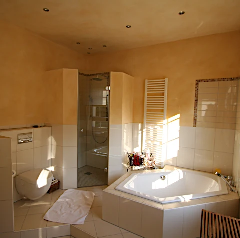 Bad mit gemauerter Duschkabine und Sechseck-Badewanne auf einem Sockel