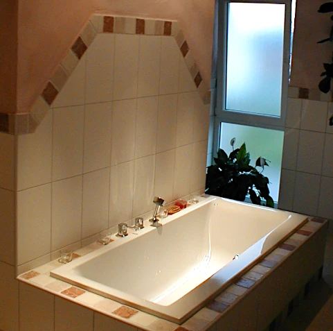 Badewanne mit gefliester Bordüre und passendem Fliesenspiegel hinter der Badewanne