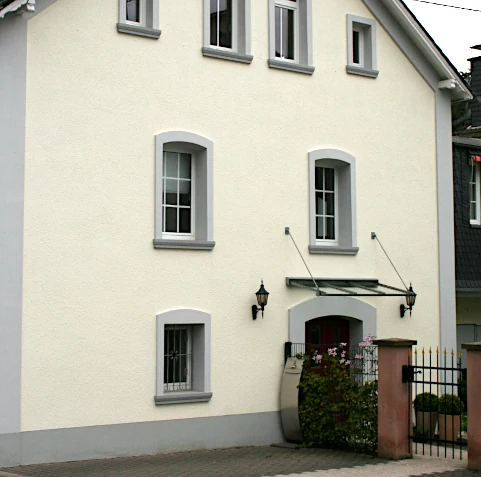 Neuer Fassadenanstrich mit grauer Einfassung der Hausränder/-kanten und Fenster