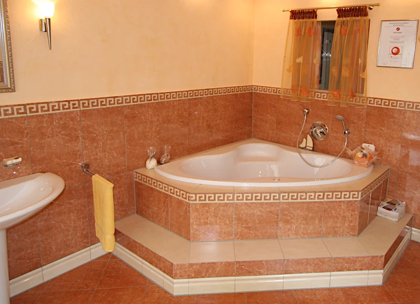 Bad mit Badewanne auf Podest mit passenden Fliesen in Terrakotta